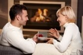 6373796-young-romantic-couple-sitting-on-couch-in-front-of-fireplace-at-home-man-giving-gift-side-view